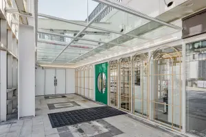 유리 캐노피와 골드 프레임의 모던 피트니스 입구